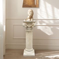 a white vase sitting on top of a wooden floor next to a painting hanging on the wall