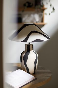 a black and white vase sitting on top of a table next to a lamp shade