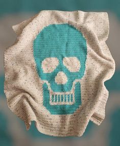 a blue and white knitted skull on a teal background