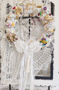 a wreath made out of lace with buttons and beads hanging on the side of a door