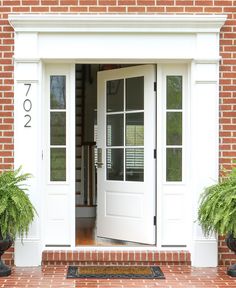 two potted plants are next to the front door and entryway with white doors