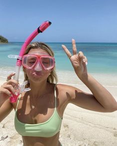 a woman wearing goggles and snorkels holds up two fingers in front of her face