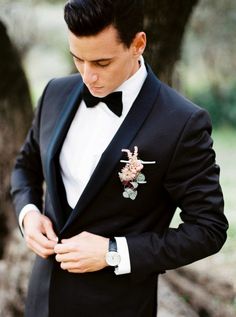 a man in a tuxedo looking at his watch