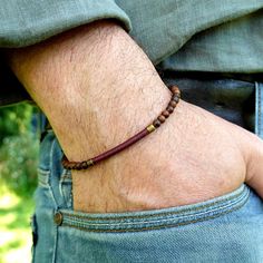 The KOZEN Burgundy Red bracelet for men combines natural elegance with a timeless, modern design. Made with genuine wood beads and a handwoven centerpiece in burgundy red linen thread, this bracelet offers both refinement and simplicity.  Ideal for men who appreciate a minimalist and authentic style, this bracelet is the perfect choice to add a touch of understated sophistication to your look.  Its adjustable size, thanks to a sliding clasp system, ensures optimal comfort and a perfect fit for w Men Boho, Beaded Bracelet For Men, Linen Thread, Boho Men, Red Bracelet, Wood Bead Bracelet, Red Bracelets, Wood Jewelry, Mens Beaded Bracelets