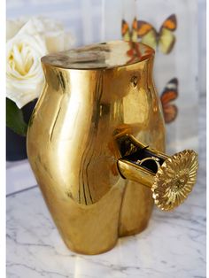 a gold elephant shaped vase sitting on top of a marble table next to a white rose