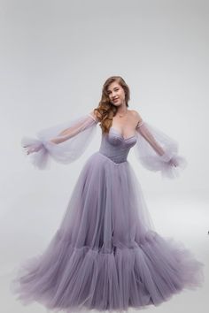 a woman in a long purple dress with her arms outstretched, posing for the camera