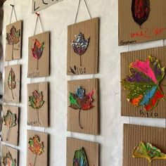 the wall is decorated with many different leaf shapes and numbers on cardboard boards, hanging from pegs