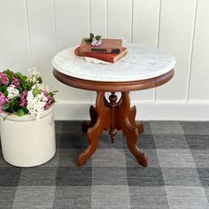 a table with flowers and books on it next to a potted plant in the corner