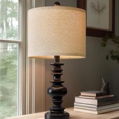 a lamp sitting on top of a wooden table next to a book shelf and window