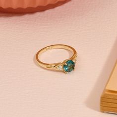 a close up of a ring on a table with a book and vase in the background