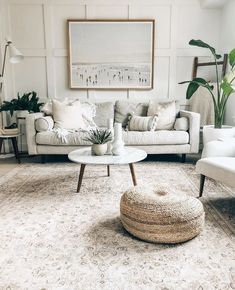 a living room filled with white furniture and lots of plants on top of the rug