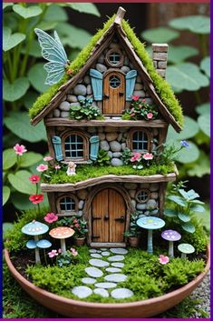 a fairy house with moss growing on the roof and windows, surrounded by flowers and rocks