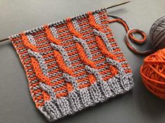 an orange and gray crochet afghan next to yarn