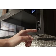 a hand is pressing the button on a microwave