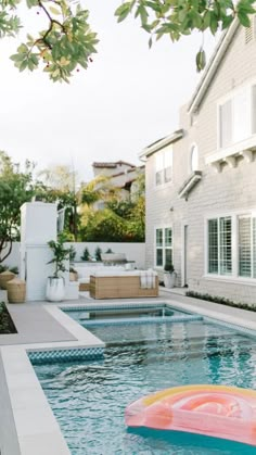 an inflatable raft floating on top of a swimming pool next to a house