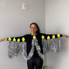 a woman standing in front of a white wall with yellow and silver decorations on her arms