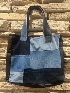 a blue and black tote bag hanging on a stone wall