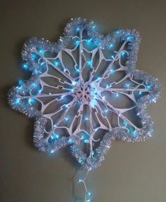 a white snowflake with blue lights hanging from it's sides on a wall