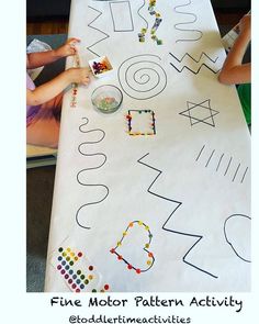 two children are sitting at a table with letters and numbers painted on the table top