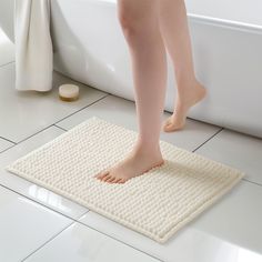 a person standing on a mat in front of a bathtub