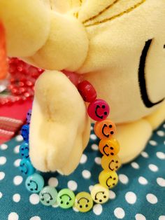 a teddy bear with beads around it's neck on a polka dot table cloth