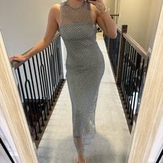 a woman is taking a selfie in the mirror wearing a silver dress and holding a cell phone to her ear