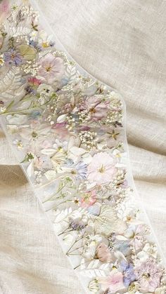 a white ribbon with flowers and butterflies on it, sitting on a cloth covered surface