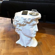 a table with a cell phone on top of it next to a statue of a man's head