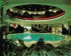 an indoor swimming pool in a hotel with lounge chairs and potted plants next to it