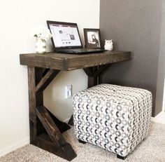 a laptop computer sitting on top of a wooden desk next to a footstool