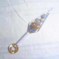 a white and gold colored object with flowers on it's side sitting on a white sheet