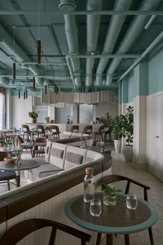 an empty restaurant with tables and chairs in the center, along with potted plants