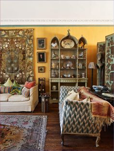 a living room filled with lots of furniture and walls covered in art nouveau style wall hangings