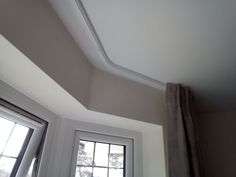 the corner of a room with two windows and a drapes hanging from it's sides