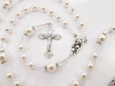 a rosary with a cross on it next to a necklace and bracelet that has pearls