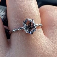 a close up of a person's hand wearing a ring with an aqua blue topazte