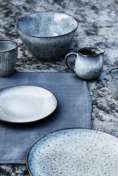 a blue place mat with dishes and cups on it, sitting next to each other