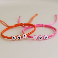 two bracelets with words written on them sitting next to each other in the shape of hearts