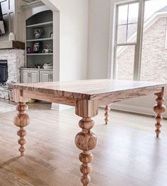 a wooden table sitting in the middle of a living room next to a fire place