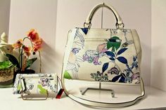 Enzo Angiolini Satchel and Wallet Set NWTs Beautiful white background with blue, pink, green, lavender floral design Measures approx 12.5"L x 9" x 5" Removable crossbody strap Dual rolled handles - 5" handle drop Interior has two compartments with a zippered divider Zippered back wall and three slip pockets on the front wall Magnetic snap closure Silver-tone hardware and name plate Matching wallet with a snap closure Measures approx 6.5"L x 3.75"H x 1"D 10 credit card slots 3 slip pockets Clear Designer Bags With Floral Print For Spring, Designer Floral Print Bags For Spring, Floral Print Formal Bags For Spring, Formal Floral Print Bags For Spring, Formal Floral Print Bag For Spring, Formal Spring Floral Print Bags, Chic Formal Bags With Floral Print, Chic Formal Bag With Floral Print, Elegant Summer Bags With Floral Print