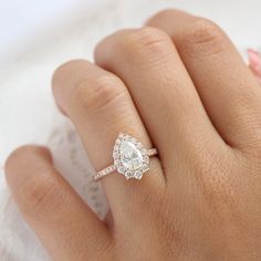 a woman's hand with a diamond ring on top of her finger and a lace doily in the background