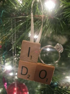 a scrabble ornament hanging on a christmas tree with the word i do spelled out