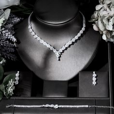 a necklace and earring set on display in a black box next to some flowers