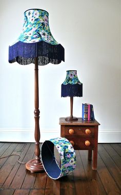 a lamp that is sitting on top of a wooden floor next to a table with books