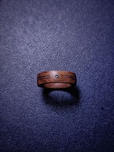 a wooden ring sitting on top of a blue surface with a diamond in the center