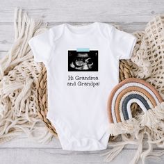 "This personalized baby outfit is a sweet way to announce your miracle on the way. Personalize it with your own ultrasound, a phrase of your choice, and the color of the \"tape\" that holds the ultrasound up (blue, pink, or yellow). HOW TO ORDER: * Select the color and size you want and add the item to your cart * Enter your personalization: What phrase you want and what color \"tape\" - blue, pink, or yellow * After purchasing, send me a message with your ultrasound photo (make sure to include White Onesie With Letter Print For Gender Reveal, Personalized White Bodysuit For Gift, Gender Reveal Onesie With Letter Print, Short Sleeve Onesie With Custom Print For Gender Reveal, Custom Print Short Sleeve Onesie For Gender Reveal, Family Matching Custom Print Onesie For Gender Reveal, Personalized White Onesie For Father's Day, Family Matching White Bodysuit For Gender Reveal, Fitted Bodysuit For Family Matching At Gender Reveal