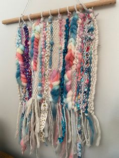 a wall hanging made out of different colored yarns and beaded with wooden pegs