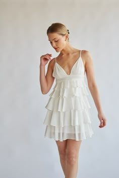 Warm sunny days just got a whole lot better with the Aria Tiered Ruffle Mini Dress! This girly dress features a v neckline, pleated waistband, and a tiered ruffle skirt. Available in azalea, black, and white. Pair with your favorite dainty accessories for the perfect summer look! Details 100% Polyester Adjustable spaghetti straps Hidden back zipper with clasp closure Dry clean only What To Wear For Graduation, White Grad Dresses, White Grad Dress, White Mini Dresses, Dresses For Graduation, Dainty Accessories, Tiered Ruffle Mini Dress, Beautiful Mini Dresses, White Bridal Dresses