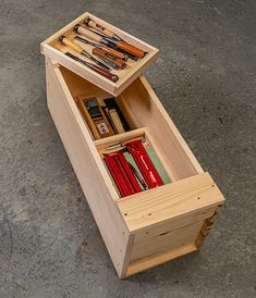 a wooden box filled with assorted items on top of a cement floor next to a wall