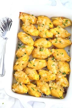 a white casserole dish filled with stuffed shells and garnished with parsley